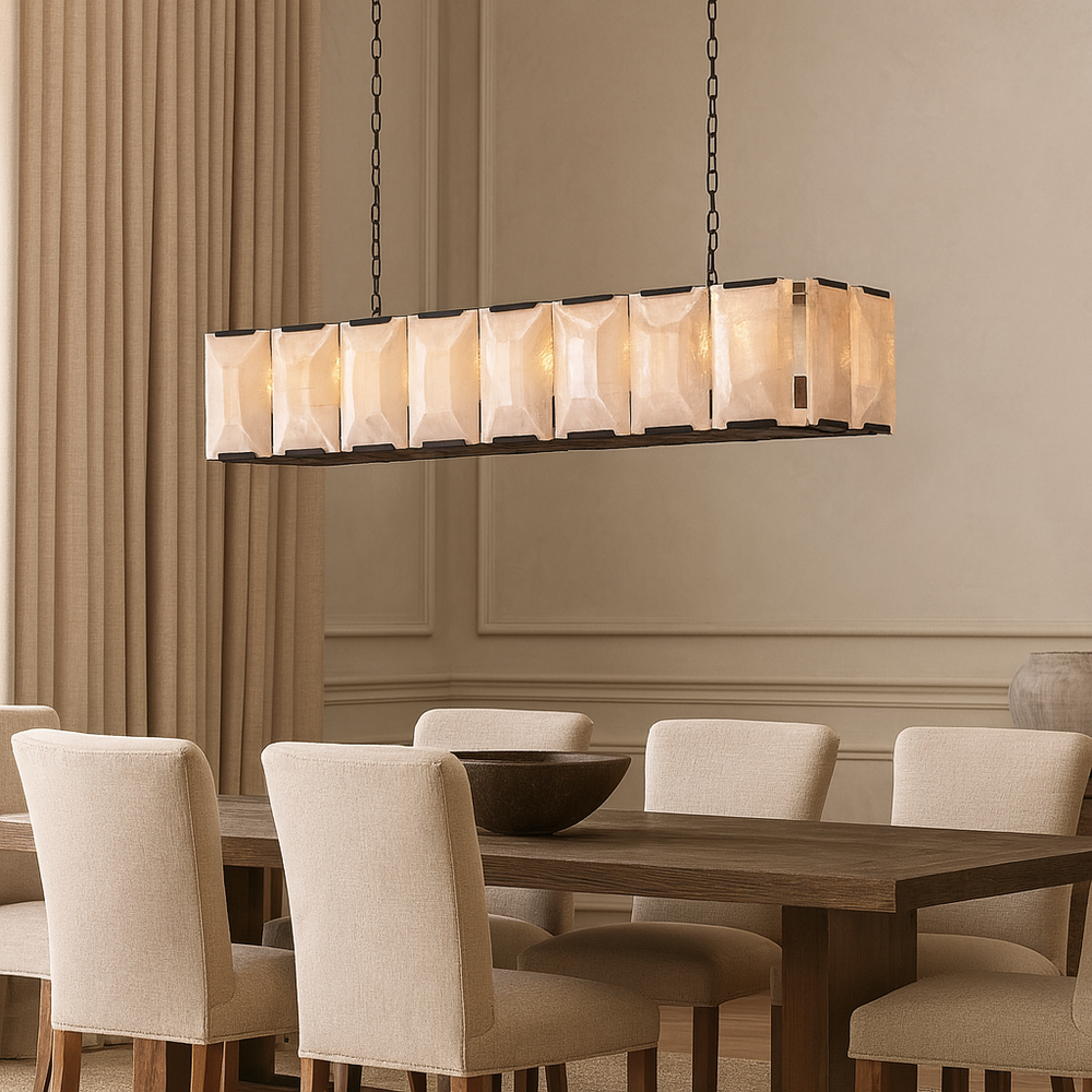 The Brookhill Calcite Dining Chandelier by Morsale.com features a translucent shade and hangs above a wooden table with six upholstered chairs in a neutral dining room, complemented by tall curtains and decorative wall molding.