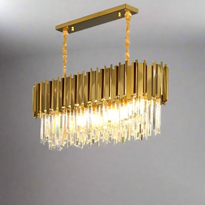 The Gio Crystal Dining Room Chandelier from Morsale.com features opulent crystal elements with sleek rectangular accents and dimmable LED bulbs. It hangs elegantly from the ceiling, casting a warm glow that enhances its sophisticated charm against a plain, light-colored backdrop.