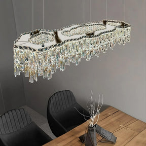 A modern, rectangular luxury Bacci Crystal Modern Dining Room Light Fixture 47" from Morsale.com, adorned with cascading crystal prisms, hangs above a dark wooden dining table. The table is set with four black cushioned chairs and a minimalist centerpiece featuring bare branches in a sleek black vase.