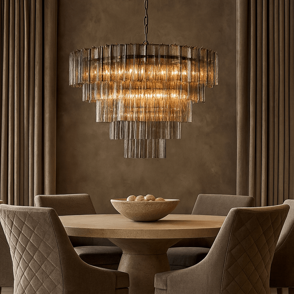 A round dining table with quilted chairs and a bowl of decorative spheres is illuminated by the Morsale Burney Modern Chandelier 35", set against floor-to-ceiling draped curtains.