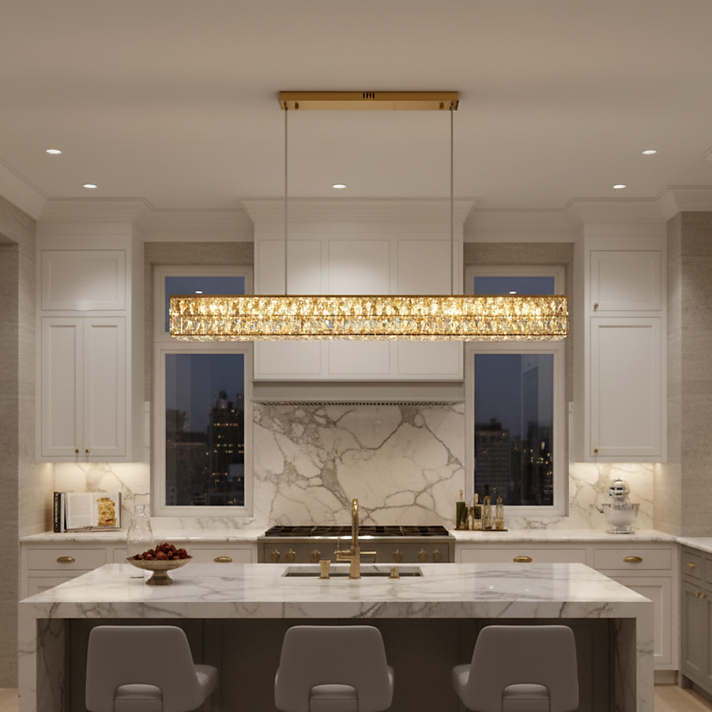 Modern kitchen with white cabinets, marble backsplash and countertops, a large island with three gray barstools, and the stunning Bacci Crystal Dining Room Chandelier by Morsale.com hanging above. City lights shine through two windows.