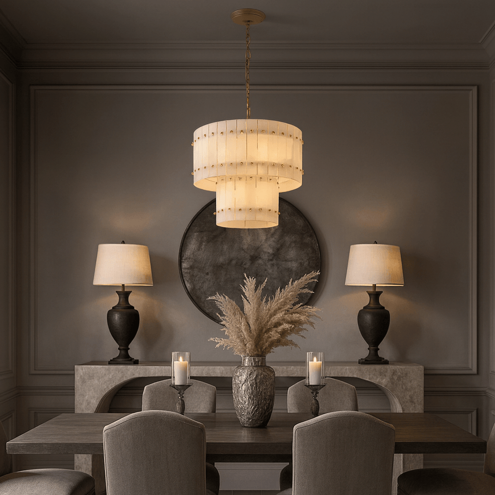 
                  
                    Elegant dining room featuring the Morsale Valmont 2-Tier Marble Chandelier 23", two table lamps on a console with a round mirror, pampas grass in a vase, and two lit candles on a dark wood table with upholstered chairs.
                  
                