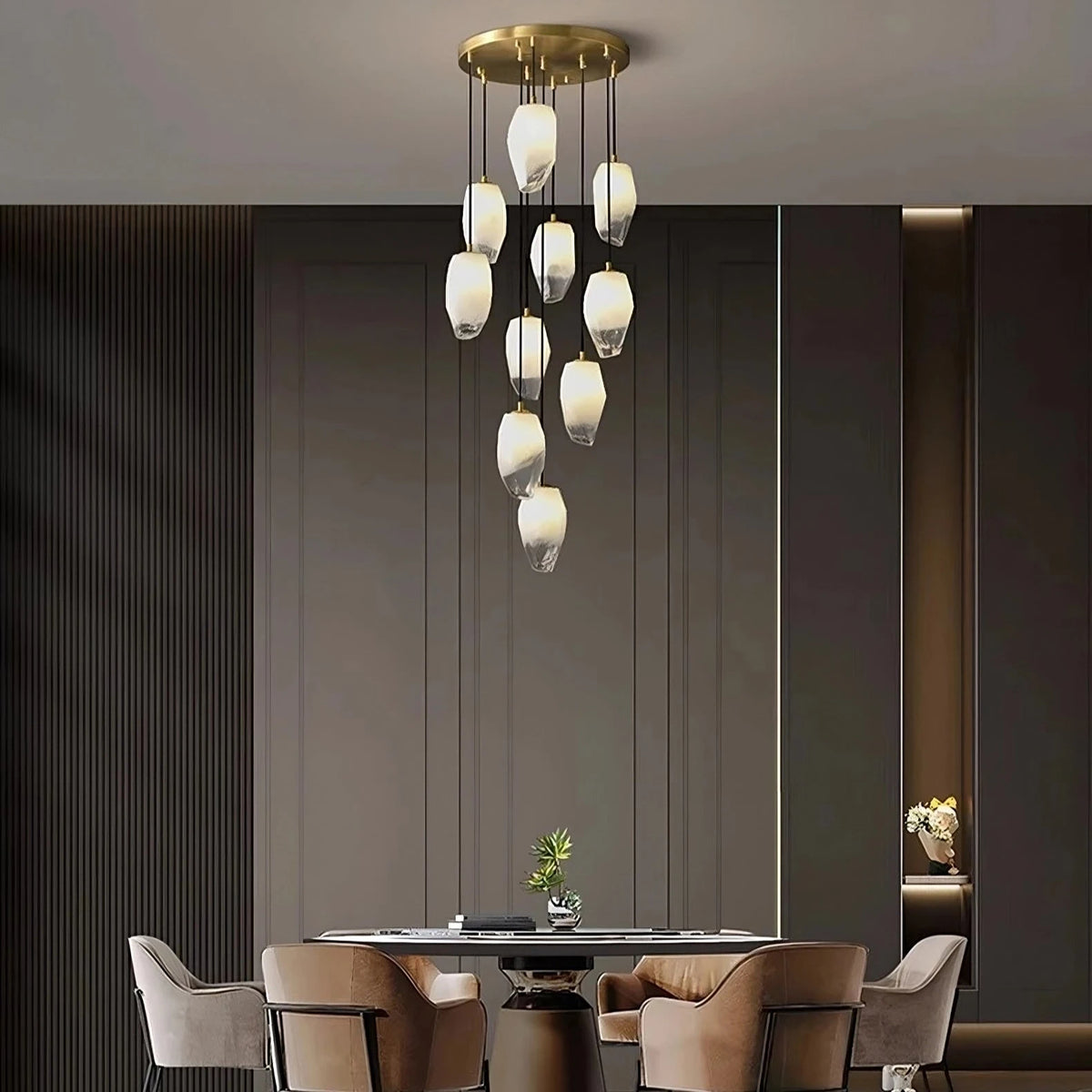 The Frost Glass Pendant Foyer Chandelier by Morsale.com is showcased, featuring multiple hanging teardrop-shaped white glass bulbs that create a cascading effect. This dimmable LED light fixture, boasting a minimalist design, is installed in a room with high ceilings, and a large window on the left offers an outdoor view.