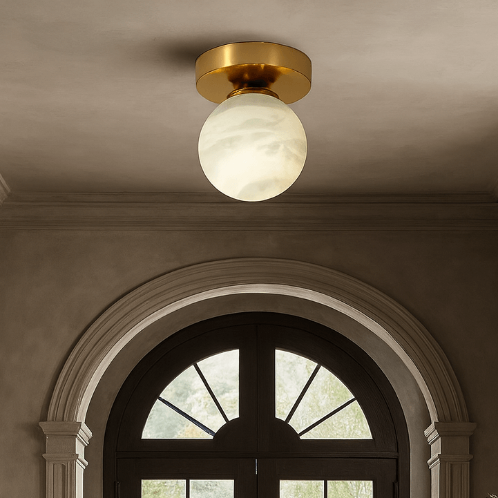 
                  
                    A hallway with arched double doors, neutral walls, molding details, and the Soria Marble Flushmount by Morsale.com. On the right side, a round table displays a vase of flowers.
                  
                