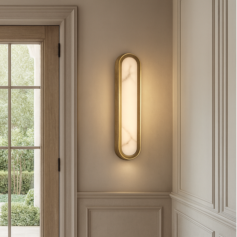 A modern entryway features double wooden doors with glass panes, beige paneled walls, and a garden view, illuminated by the Morsale Solari Marble & Brass Sconce, which casts a soft, elegant glow.