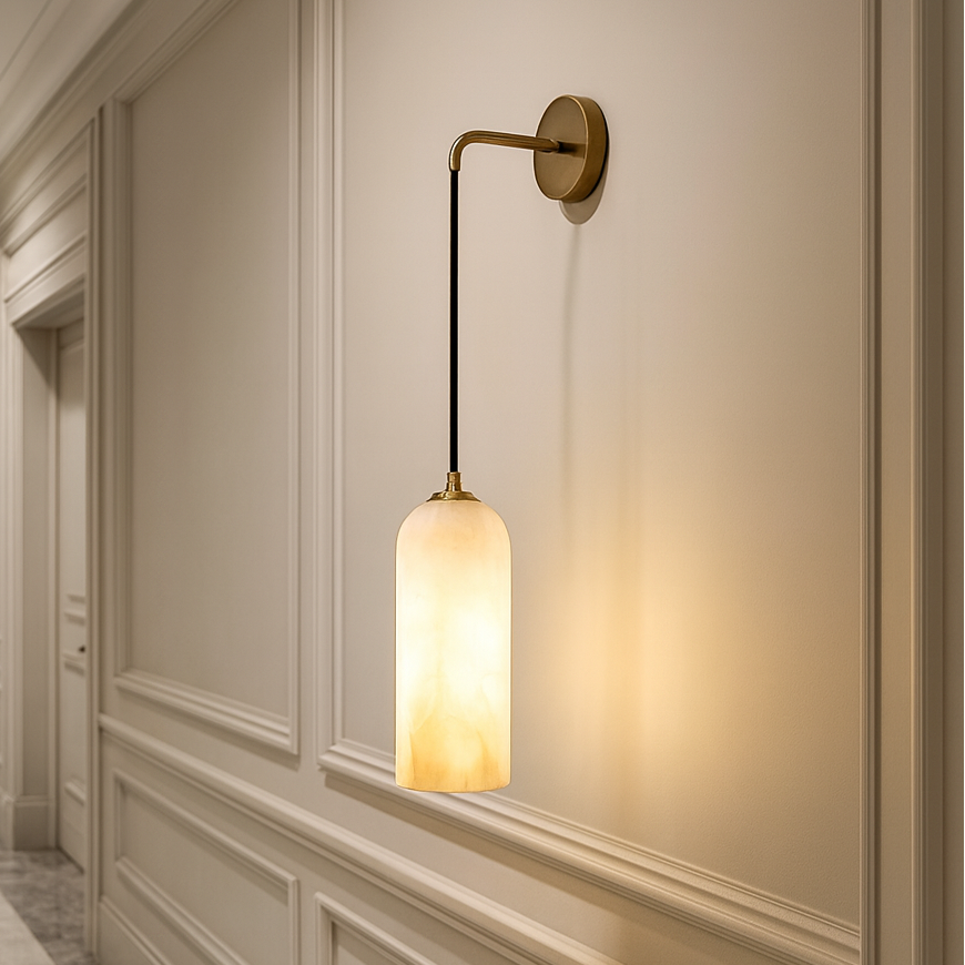 A hallway with cream paneled walls and a marble floor features the Mirasol Marble Sconce by Morsale.com, its brass design and frosted glass shade casting a warm glow.