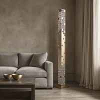 A modern living room with a beige sofa, wooden coffee table holding two gold bowls, and the Morsale Aurelia Crystal Tower Floor Lamp—an elegant geometric crystal design—illuminating the space beside soft beige curtains.