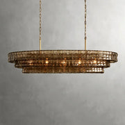 The Morsale Riviera Vintage Glass Dining Room Chandelier features elegant brownish glass tiers in an oval shape, gracefully suspended by two golden chains. It casts a warm glow against a plain light gray wall, perfect for dining room lighting.