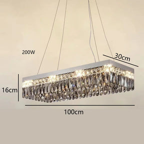 A Giano Crystal Ceiling Light by Morsale.com, a luxury rectangular crystal chandelier with dimensions: 16 cm height, 30 cm width, and 100 cm length, suspended from the ceiling by two wires. This handmade Venice flush mount crystal chandelier is lit up and has a power rating of 200W. The crystals are arranged in rows along the bottom.
