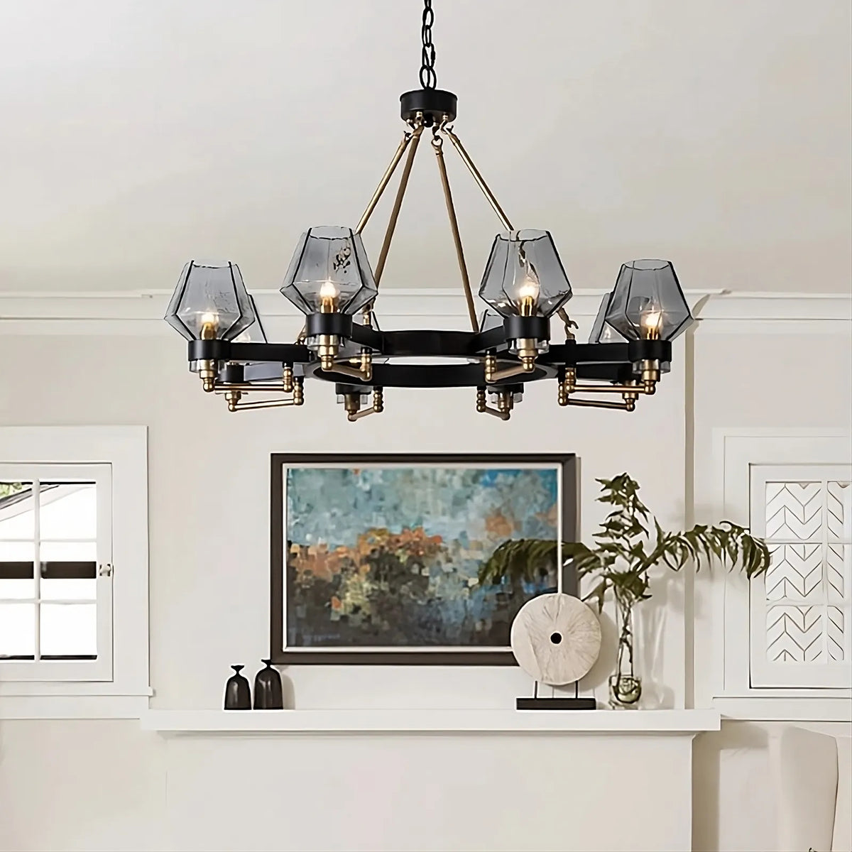A modern living room features a timeless lighting option with a black and gold Morsale.com Retro American Pendant Chandelier Light Fixture, boasting six geometric glass light shades suspended from the ceiling. Below, there's an abstract painting, potted plant, decorative sculptures, and a window with white trim. The room's decor is contemporary.