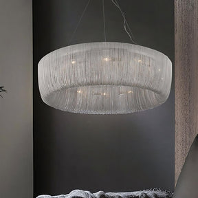 The Cadena Chain Tassel Chandelier Light from Morsale.com hangs from the ceiling, featuring multiple strands of metallic chains that create a shimmering effect. The soft, diffused light it emits illuminates the dark, minimalist room, adding an elegant, contemporary touch to the space.