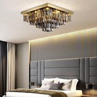 Gio Smoke Grey Crystal Chandelier illuminating a modern bedroom with a stylish design.