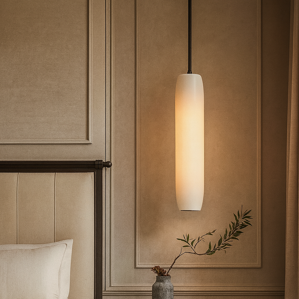 The Moonshade Marble Pendant by Morsale.com hangs beside a beige upholstered bed and a gray vase with a leafy branch, set against elegant paneled walls in a softly lit room.