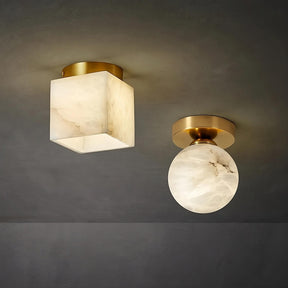 An image showing two ceiling lights with a modern design. One **Natural Marble Hallway Ceiling Light Fixture** by **Morsale.com** has a cube-shaped frosted shade, and the other has a round frosted shade. Both lights have gold-toned fixtures and are mounted on a dark gray ceiling.