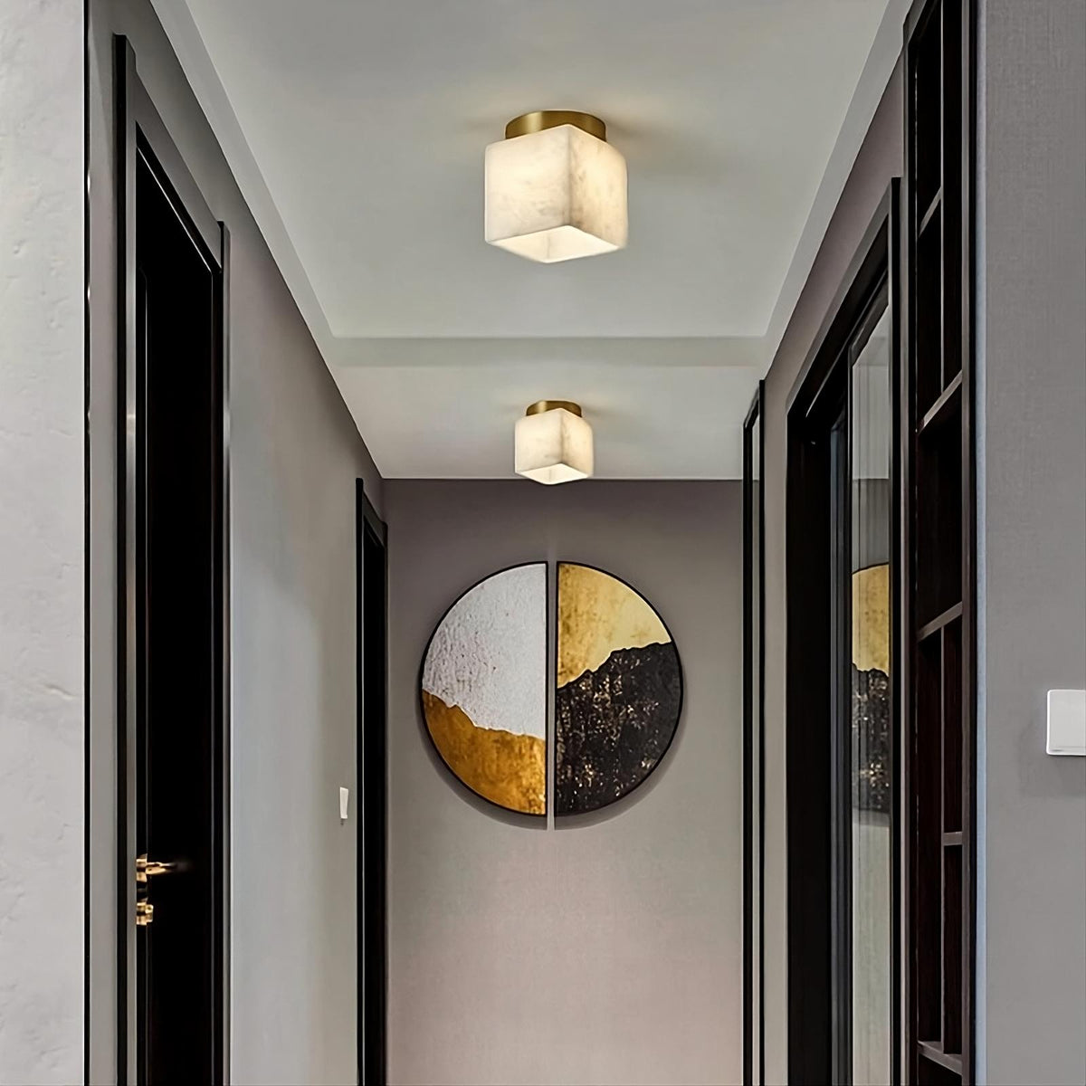 A narrow hallway featuring two modern LED light fixtures with cubic designs. The corridor, painted gray with black trim on the doors, is adorned with Spanish marble flooring. At the end of the hallway, a Natural Marble Hallway Ceiling Light Fixture by Morsale.com catches the eye.