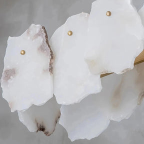 Close-up of irregularly shaped white marble pieces with brass pins on a light grey background. The text below reads "High quality natural marble (Effect of turning off lights)." Some marble pieces exhibit subtle brown and grey veins, ideal for a Natural Marble Modern Chandelier by Bigman.