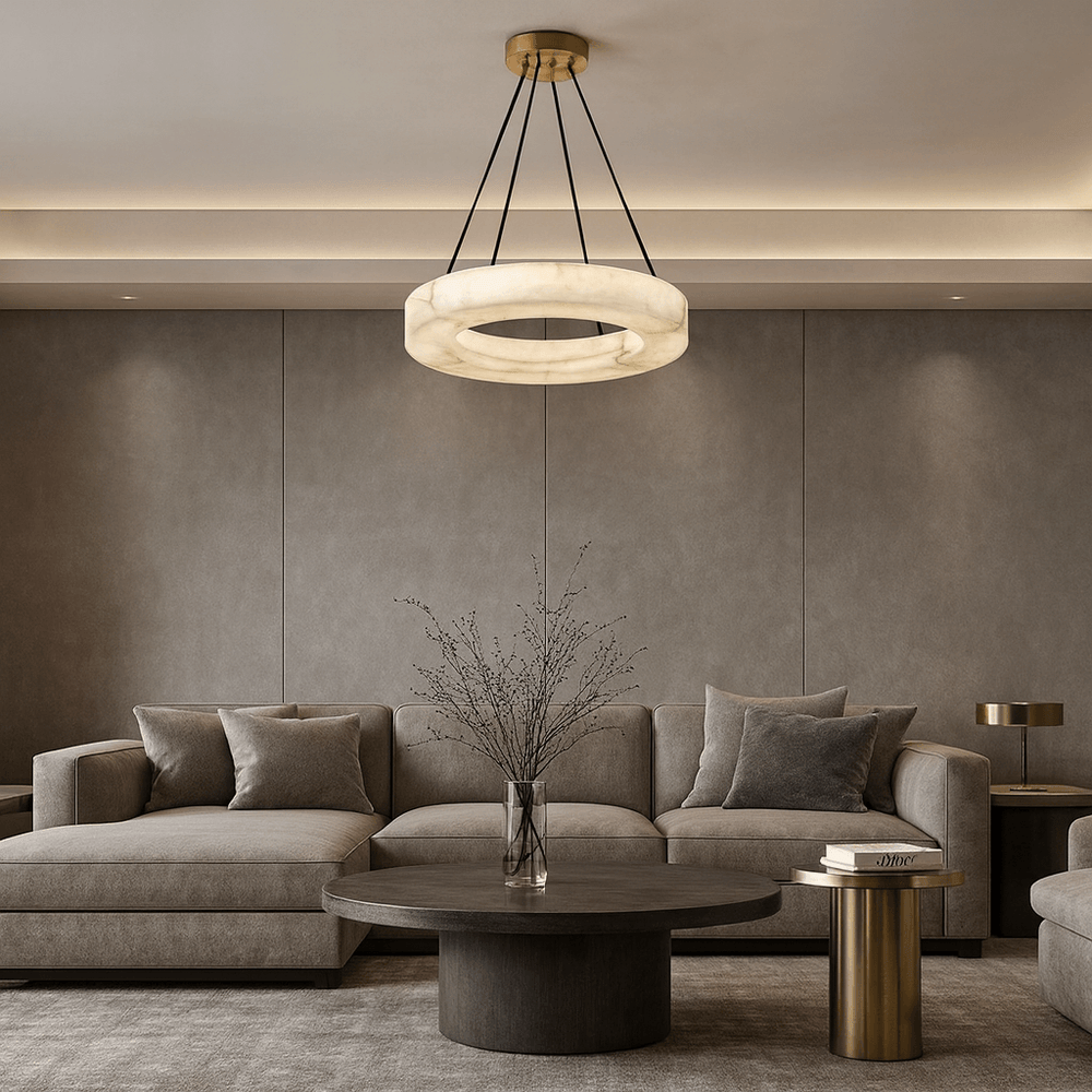 
                  
                    A modern living room with neutral tones features a large sectional sofa, a round dark coffee table with a vase of branches, a gold side table, and the elegant Morsale Palmer Marble Chandelier hanging from the ceiling.
                  
                