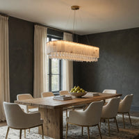 Dining room with wooden table and white chairs under a modern chandelier.