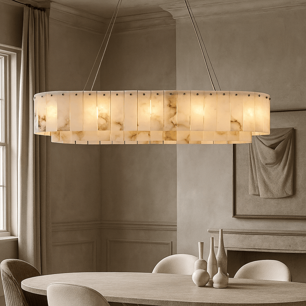 The Matwell Marble Chandelier by Morsale, featuring translucent oval panels, casts a warm glow above a round dining table with vases in a neutral-toned room with elegant wall molding and draped fabric art.