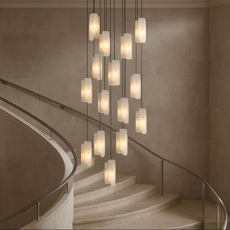 The Lunara Marble Chandelier by Morsale hangs above a curved staircase with a metal handrail, adding modern luxury lighting to the neutral-toned, minimalist interior.