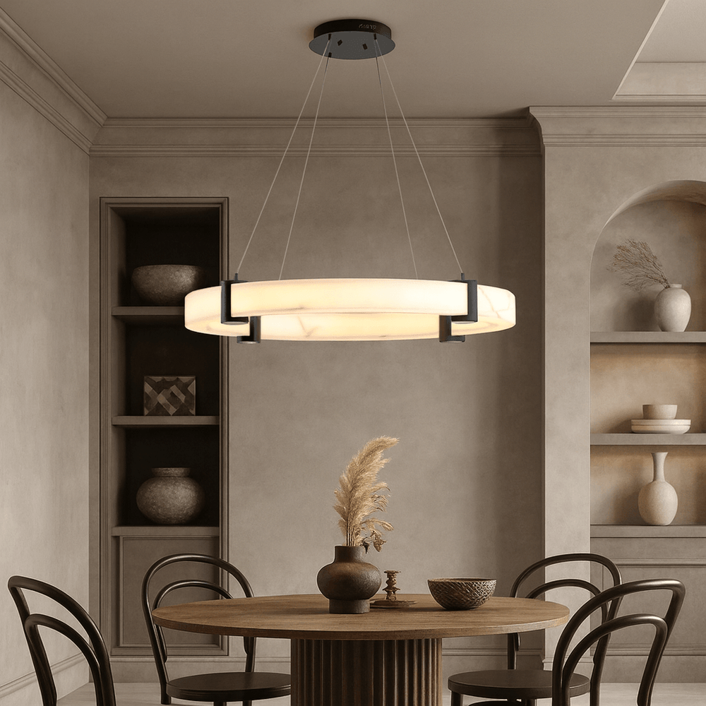A modern dining room with a round wooden table, four chairs, built-in shelves with pottery, a vase of dried plants, and the Chester Marble Ring Chandelier by Morsale, adding striking contemporary flair to the space.
