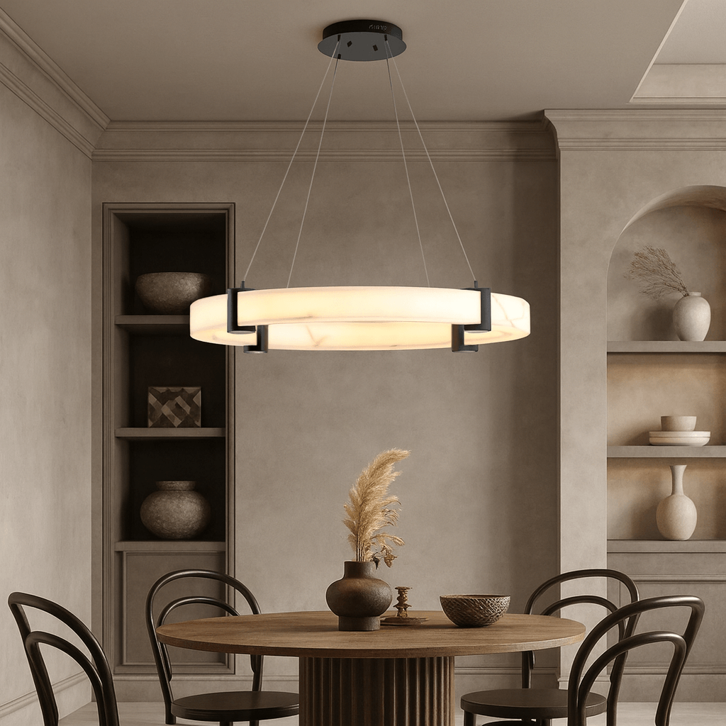 A modern dining room with a round wooden table, four chairs, built-in shelves with pottery, a vase of dried plants, and the Chester Marble Ring Chandelier by Morsale, adding striking contemporary flair to the space.