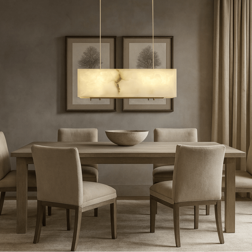 
                  
                    A minimalistic dining room with a rectangular wooden table, six beige upholstered chairs, a round bowl centerpiece, two framed tree prints, floor-length beige curtains, and the Leroy Marble Chandelier by Shopp578 overhead.
                  
                