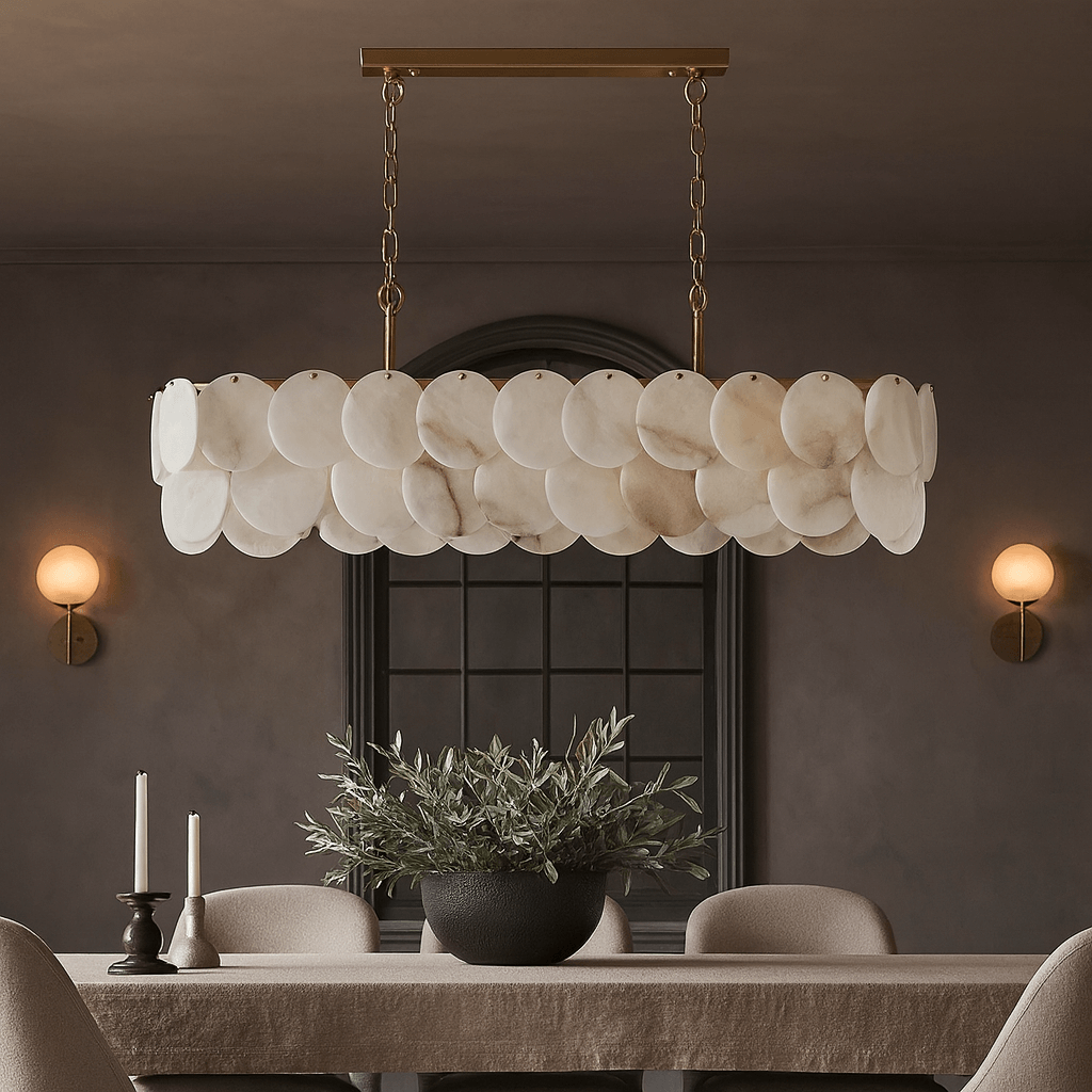 A modern dining room highlights the Morsale Bordwell Marble Dining Room Chandelier 47" above a rectangular table with candles, a potted plant, neutral chairs, and two wall sconces on dark walls.