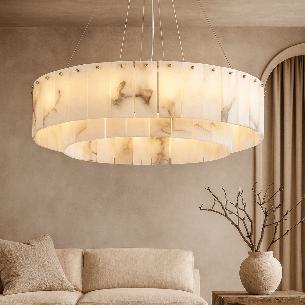 
                  
                    The Bigman Buckley Marble Modern Chandelier hangs above a beige sofa in a neutral living room. A vase with bare branches is on the side table, while soft curtains frame an arched wall opening.
                  
                