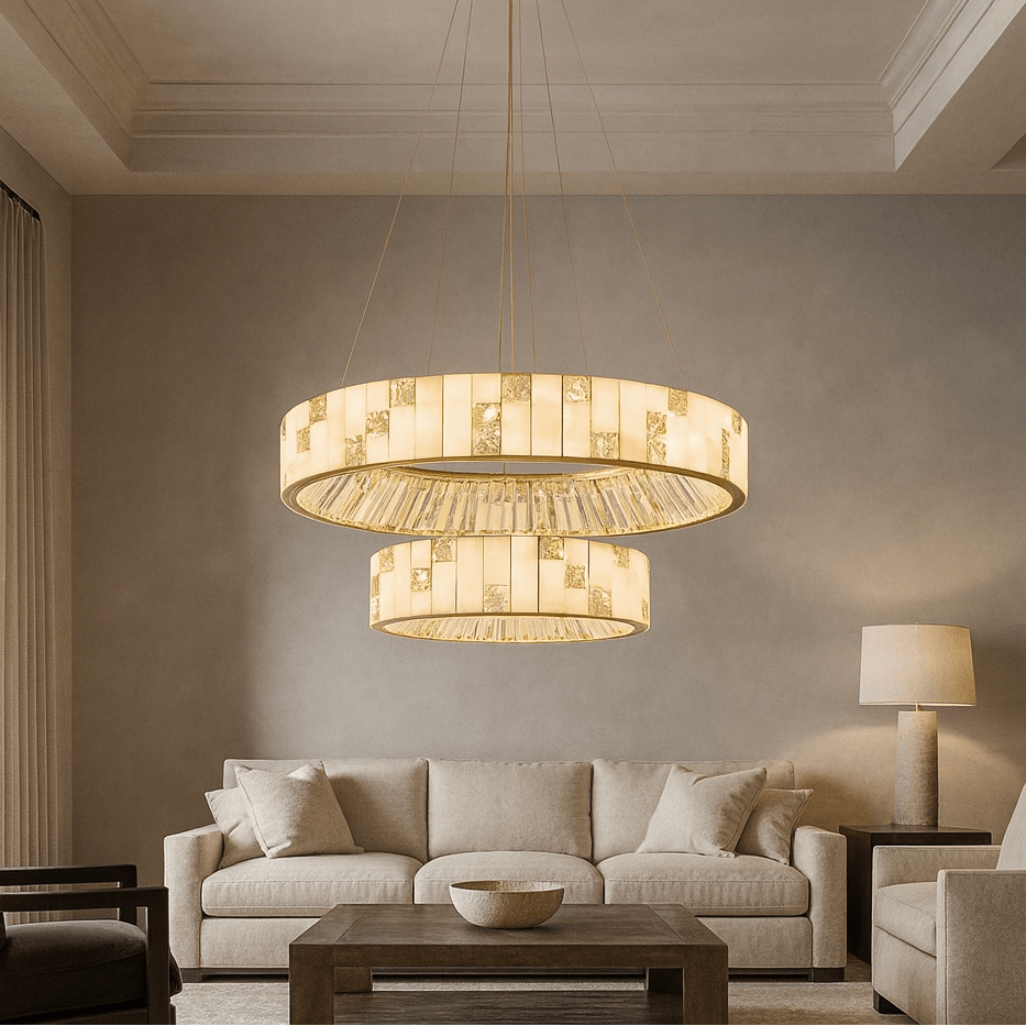 A modern living room with a beige sofa, coffee table, and armchair, featuring two Morsale Edes Crystal & Marble Chandeliers suspended from the ceiling, casting warm light and complementing the neutral, elegant decor.
