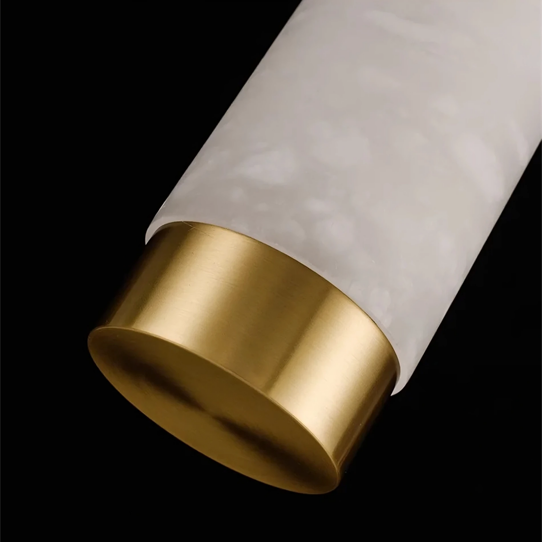 Close-up of the Moonshade Natural Marble Dining Room Light Fixture by Bigman, showcasing its cylindrical design with a white, marble-textured upper part and a shiny gold-colored metallic base. Set against a black background, the white and gold elements combine to create an elegant, modern minimalistic appearance.