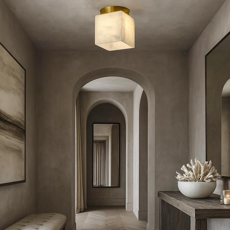 A stylish hallway with arched doorways, neutral-toned walls, a Soria Marble Flushmount by Morsale.com for luxury lighting, a bench, large mirrors, abstract art, and a wooden table adorned with coral decor and a lit candle.