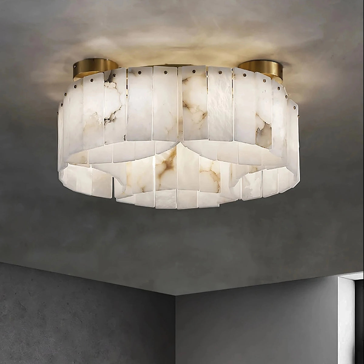 The Moonshade Natural Marble Ceiling Light Fixture by Morsale.com is a modern ceiling fixture with a circular design, featuring vertically arranged rectangular pieces crafted from natural marble and brass. It emits warm lighting and is mounted on a grey ceiling in a minimalist room with dark walls, enhancing the modern aesthetic.