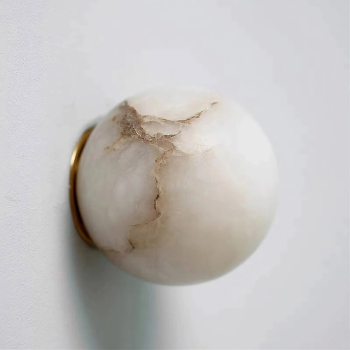 The Moonshade Marble Ball Light Fixture by Morsale is a spherical white marble lamp with brown veins, mounted on the wall with a gold metallic ring. Its sleek design and polished surface offer a minimalist look, enhanced by an energy-efficient LED bulb.