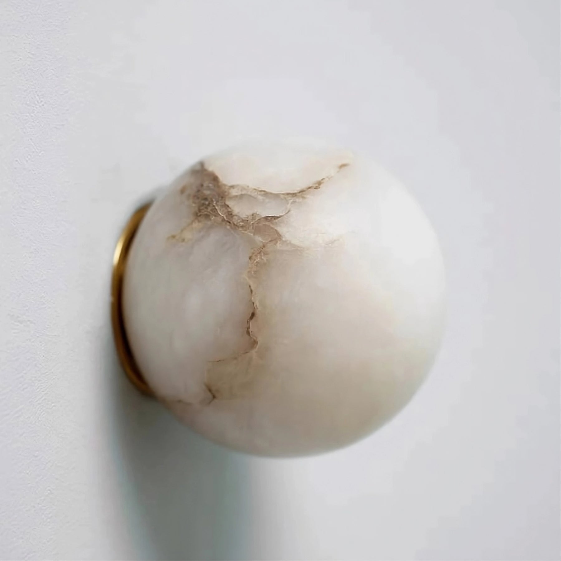 The Moonshade Marble Ball Light Fixture by Morsale is a spherical white marble lamp with brown veins, mounted on the wall with a gold metallic ring. Its sleek design and polished surface offer a minimalist look, enhanced by an energy-efficient LED bulb.