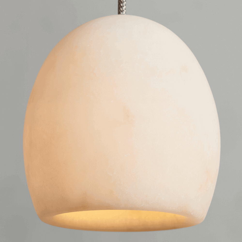 The Auris Marble Pendant by Morsale.com features a dome-shaped, off-white marble shade with a smooth finish, softly glowing against a gray backdrop—an elegant lighting choice for contemporary interiors.