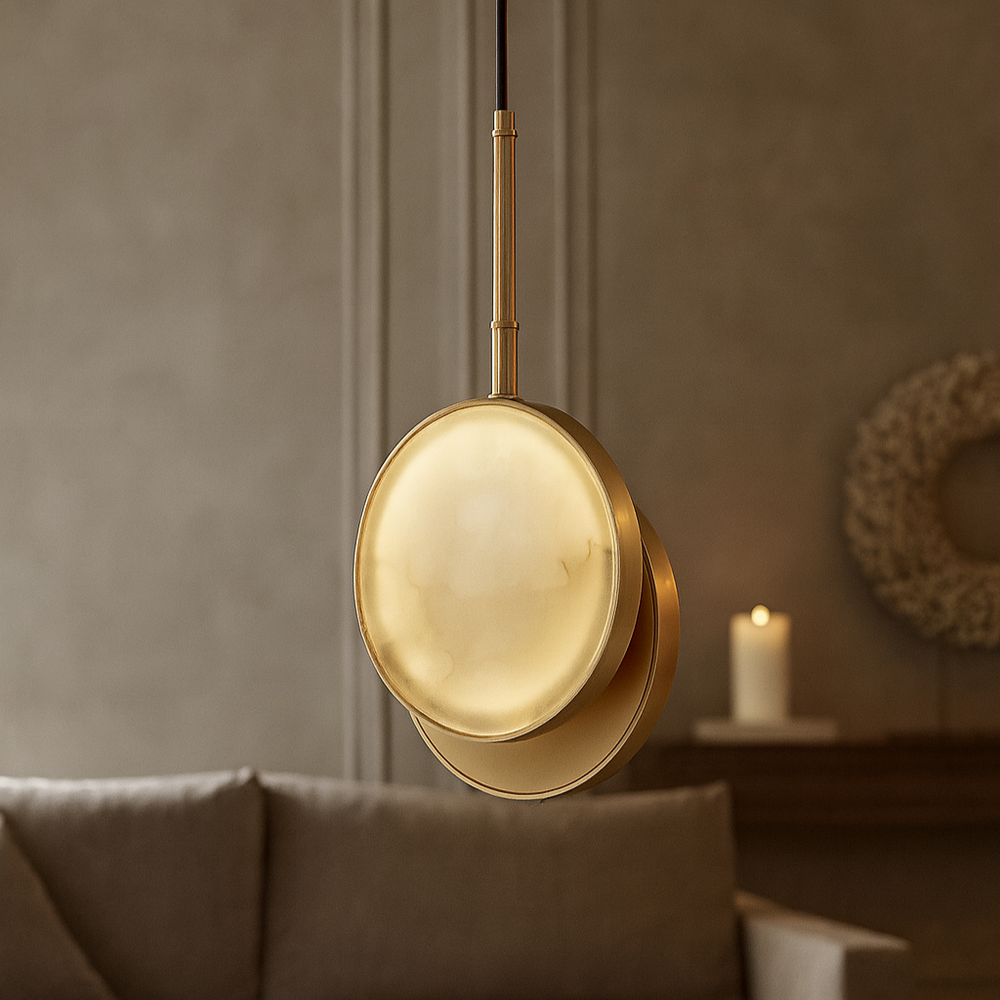 
                  
                    A modern Aeris Marble Pendant Light by Morsale.com with a round, frosted glass shade hangs in a softly lit living room featuring a beige sofa and a lit candle on a wooden shelf in the background.
                  
                