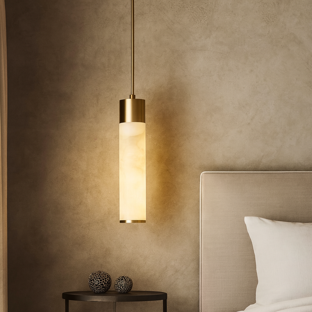 The Sorella Marble Pendant by Morsale.com, featuring a cylindrical frosted glass shade, hangs beside a beige bed. A round black side table with two decorative spheres is set against a textured neutral wall.