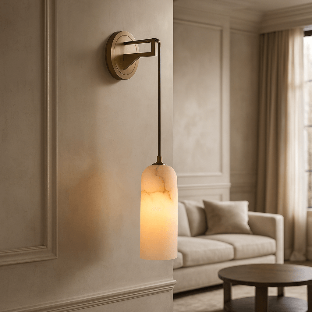 The Lucera Marble Pendant Sconce by Morsale features a brass finish and frosted glass, casting a warm glow in an elegant living room with a beige sofa, round table, and large window with curtains.