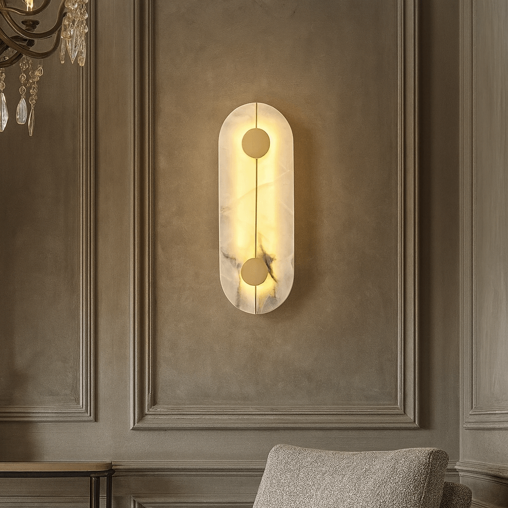 The Haddon Marble Sconce by Morsale.com features an oblong design and a soft, warm glow, elegantly mounted above a textured beige armchair on a paneled wall.