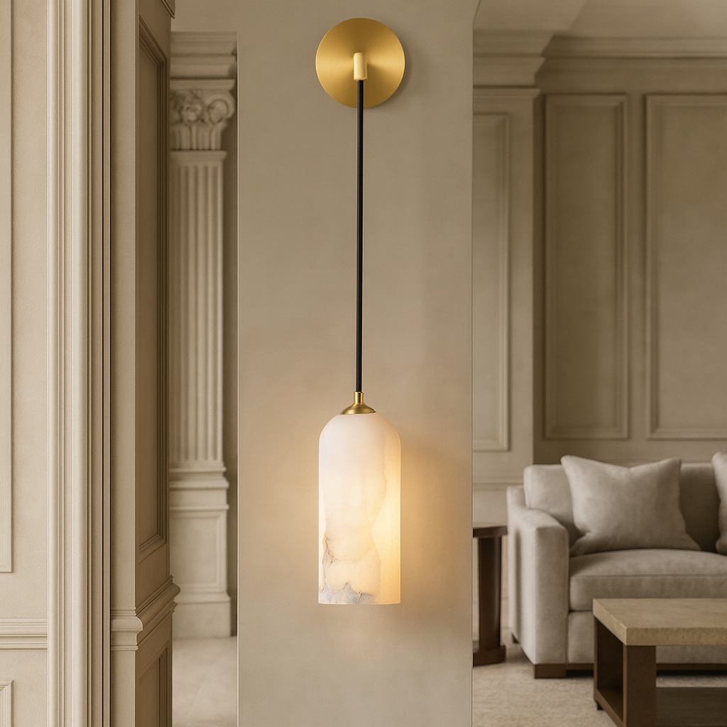 The Mirasol Marble Sconce by Morsale.com, featuring a gold fixture and frosted glass shade, casts a warm glow on a beige wall in an elegant living room with classic details and neutral furnishings.