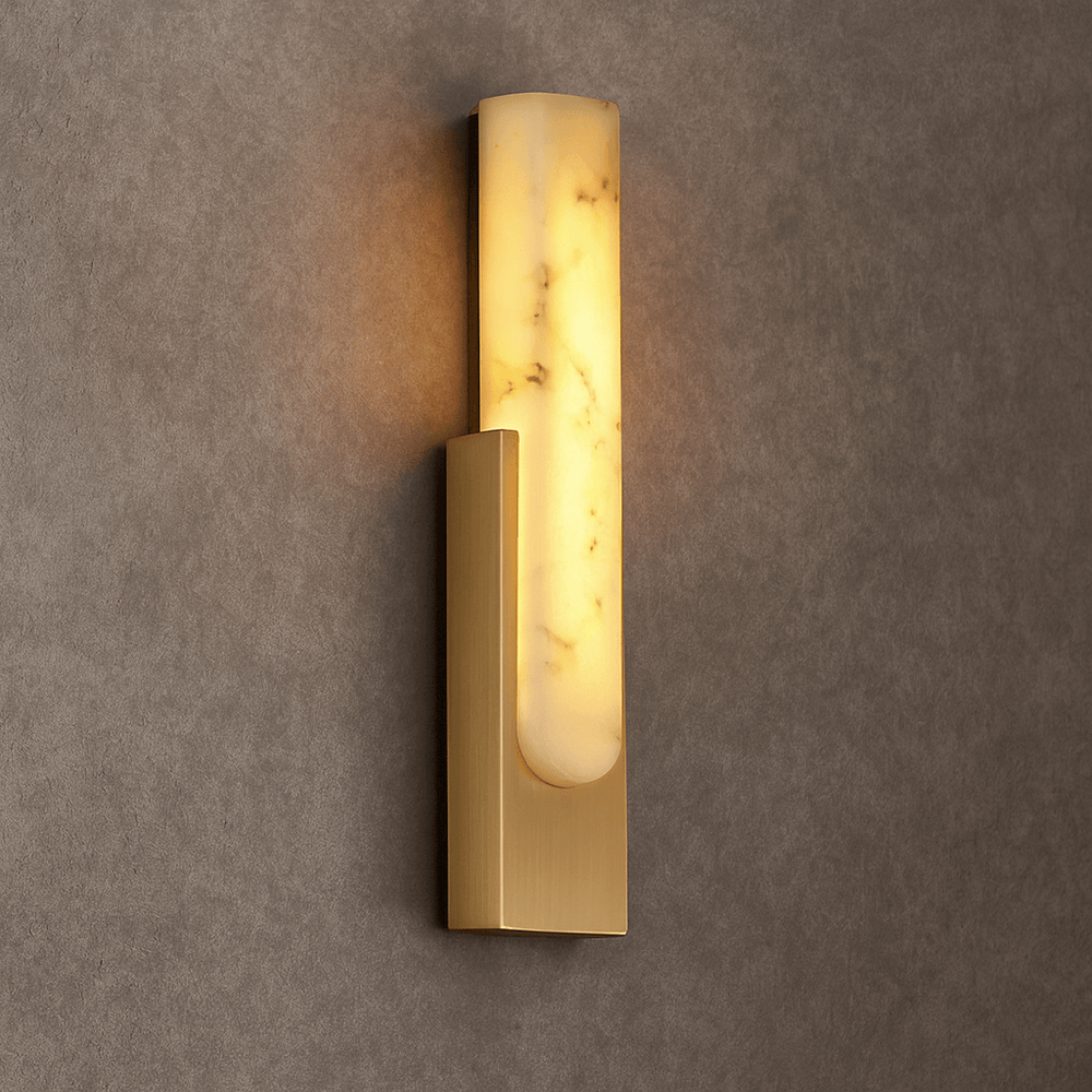 
                  
                    The Wexford Marble Wall Sconce by Morsale.com features a brushed gold rectangular base and a tall frosted glass shade, casting warm light and adding elegant style to any textured taupe wall.
                  
                