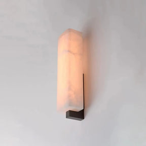 The Alton Marble Wall Lamp by Morsale has a rectangular, translucent alabaster shade that provides a soft, warm glow with its LED light, mounted on a dark, minimalist metal bracket on a white wall.