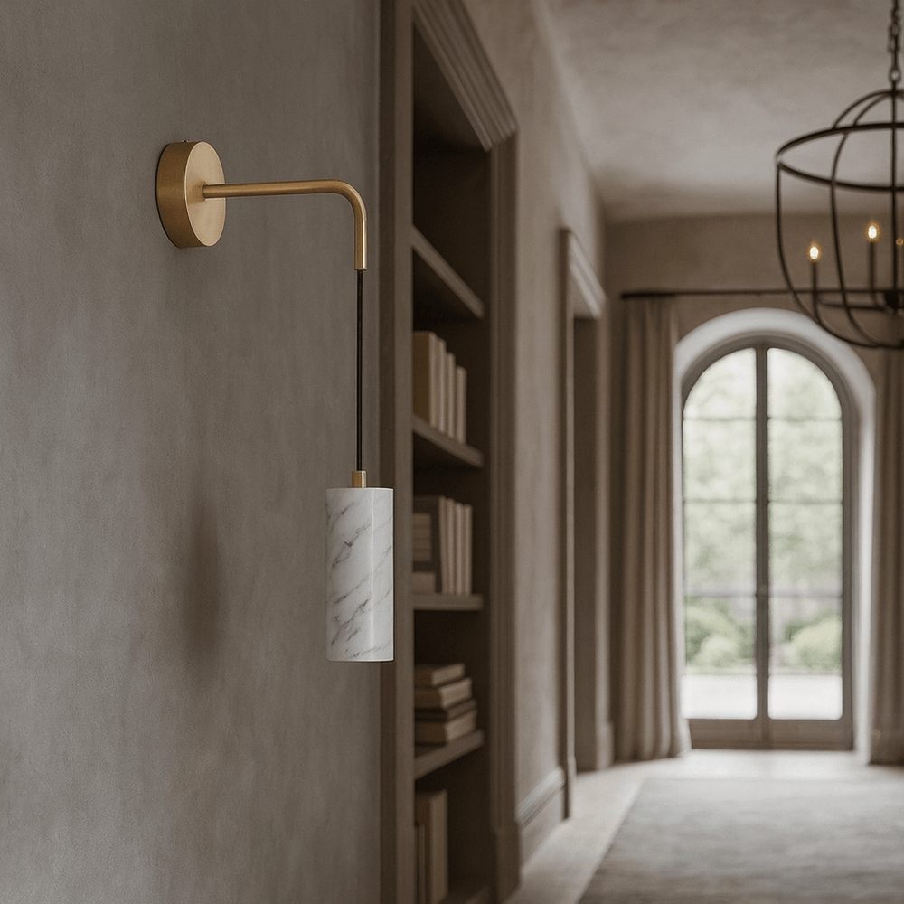 
                  
                    The Biltmore Marble Pendant Wall Sconce by Morsale, featuring a gold arm and natural marble shade, is mounted in a neutral hallway with built-in shelves, an arched window, and a large chandelier in the background.
                  
                