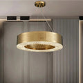 The Giovanni Modern Chandelier by Morsale.com features a stainless steel textured circular frame and clear crystal accents, adding elegance to a stylish living room with paneled walls and neutral decor.