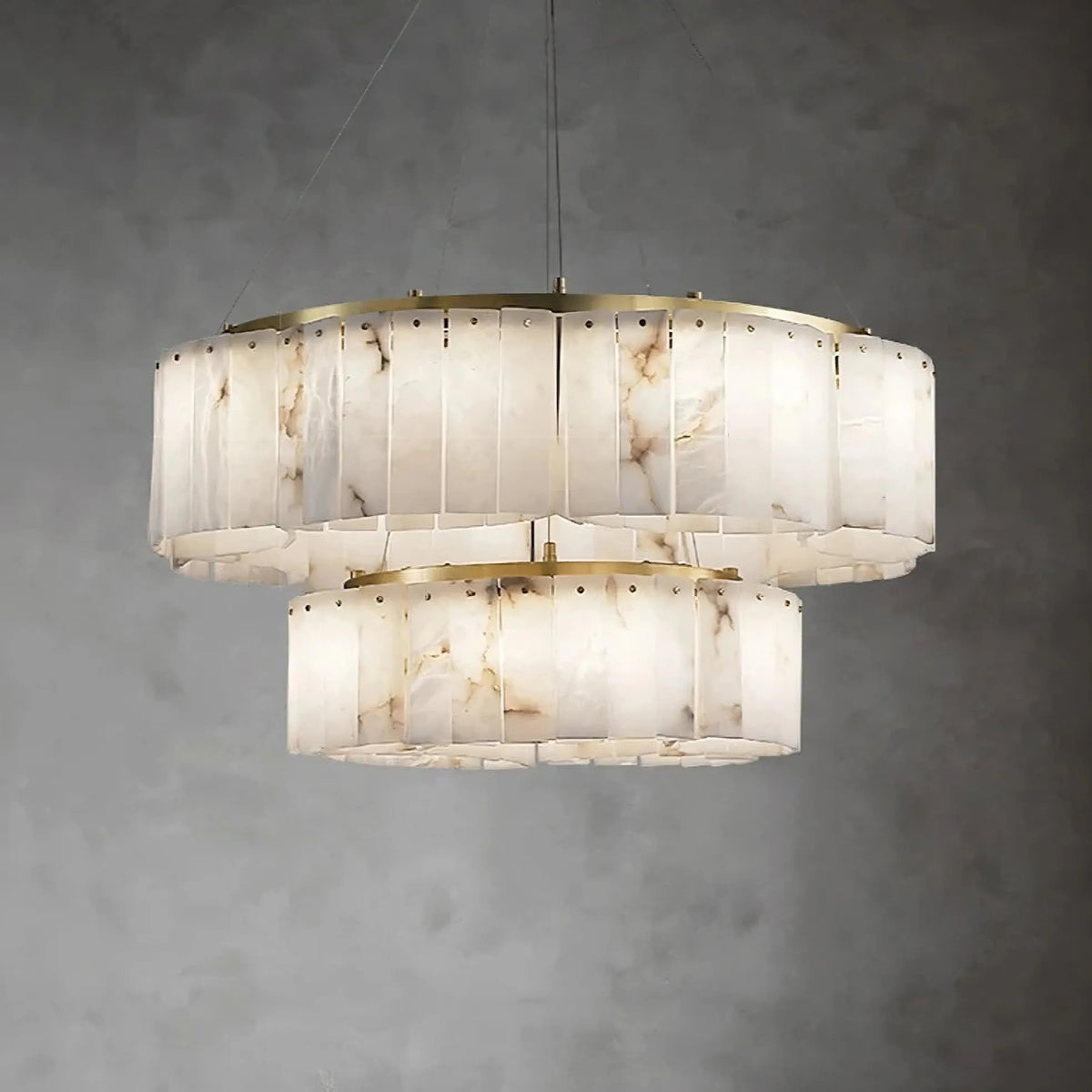 A modern chandelier with dual tiers, showcasing an alabaster and metal design with subtle copper accents. The *2-Tier Natural Marble Modern Chandelier* by *Morsale.com* features two concentric cylindrical lampshades with a natural marble pattern that emits a soft, diffused light against a gray, textured background.