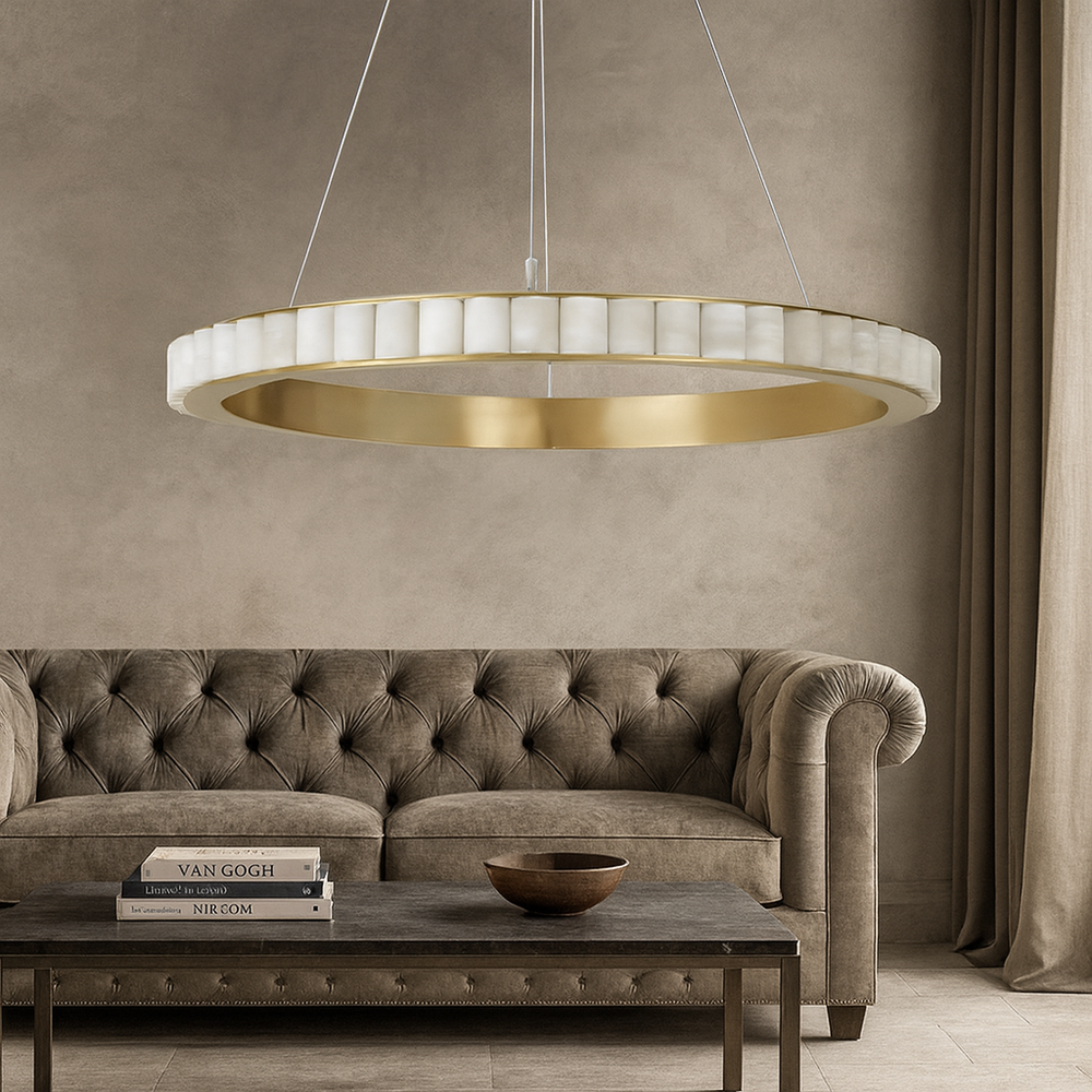 
                  
                    A modern living room features a tufted beige sofa, a dark coffee table with books and a bowl, and the Bigman Hampton Marble Chandelier with gold and white accents overhead. Neutral-toned walls and curtains complete the minimalist decor.
                  
                