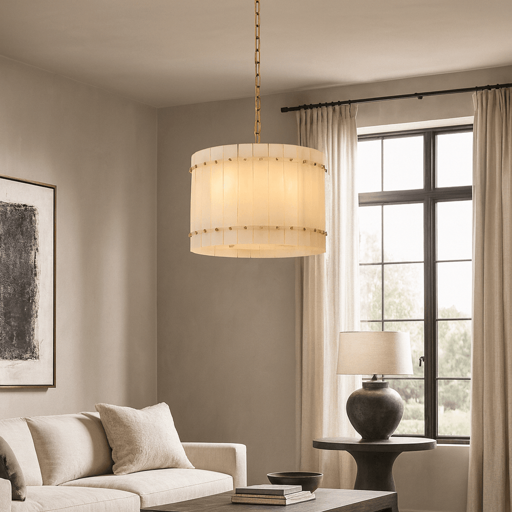 
                  
                    A modern living room with a beige sofa, abstract wall art, a large window with light curtains, a black side table with a lamp, and the Morsale Valmont Marble Round Chandelier 16" elegantly hanging from the ceiling.
                  
                
