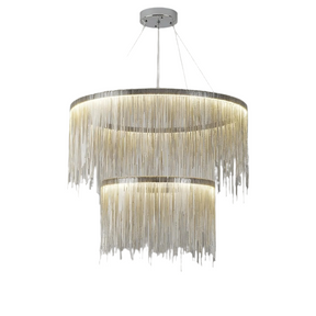 The Cadena Steel Tassel Modern Chandelier by Morsale.com, featuring multiple layers of cascading thin golden chains in a large circular design, serves as the focal point with its sleek LED light source. The backdrop of marble walls with a white and gray veined pattern underscores the elegance of the modern interior design.