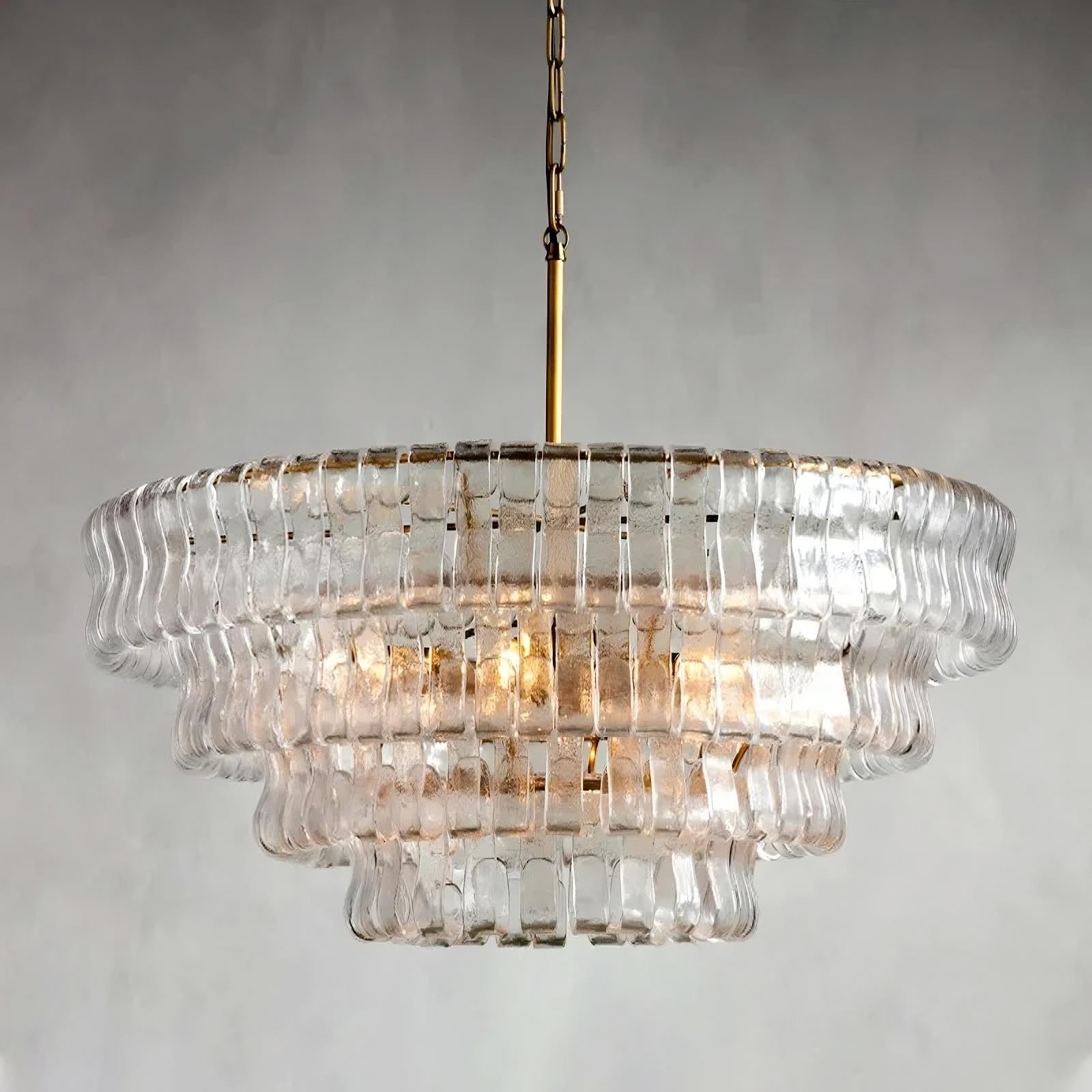 The Morsale Riviera Vintage French Crystal Chandelier, with its brass rod and chain, hangs elegantly from the ceiling. Its clear, rippled glass pieces are tiered beautifully, offering a classic touch against a plain gray background.